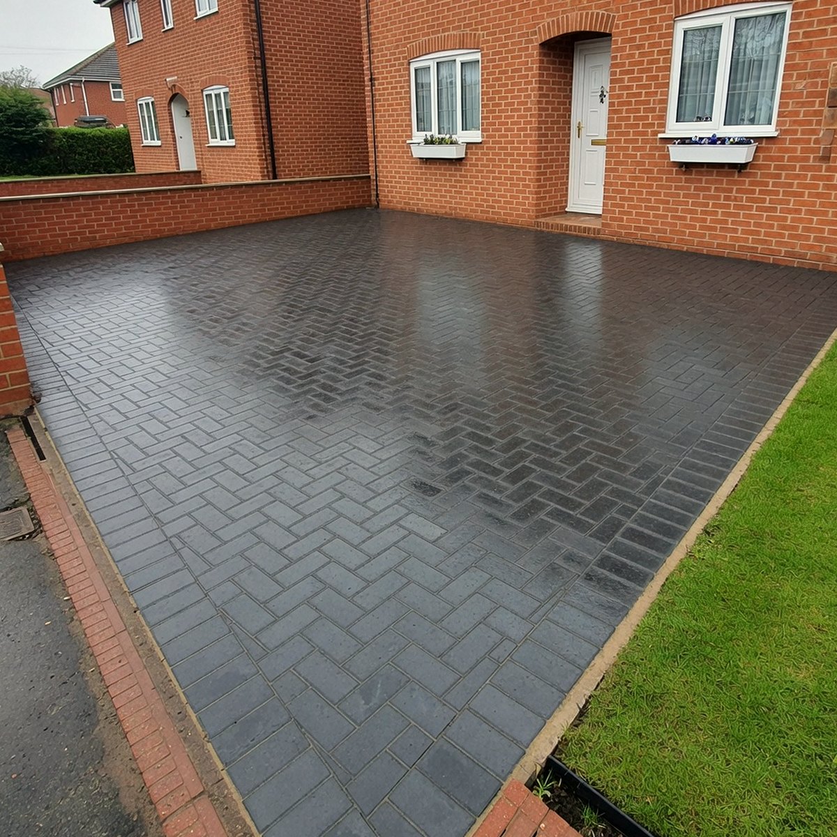 Newly laid charcoal block paving driveway in front of a British brick house